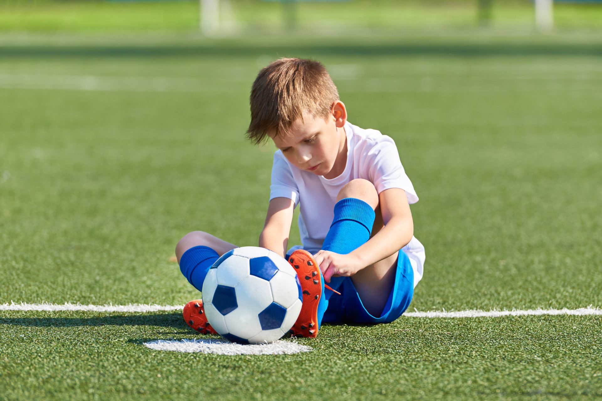What Size Soccer Ball For 5 Year Old - boy sitting on a soccer pitch