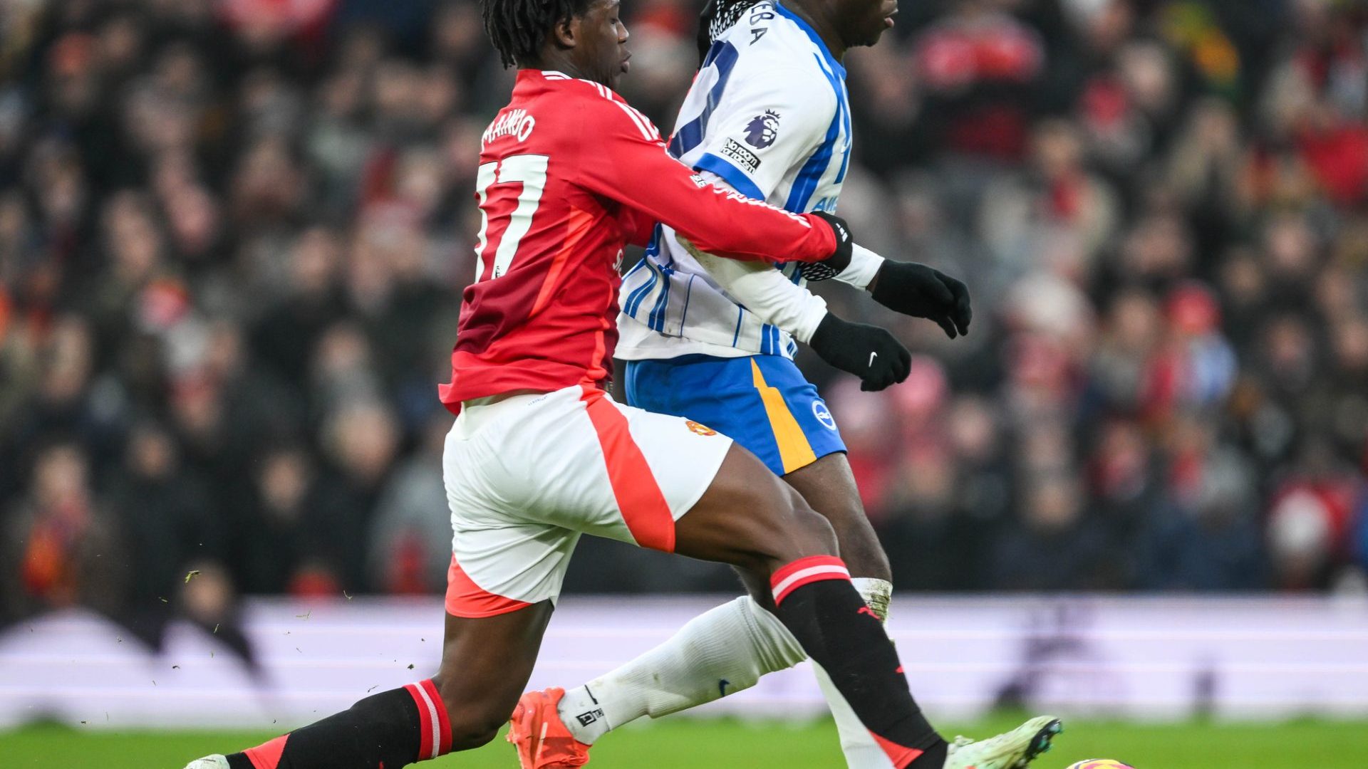 Carlos Baleba of Brighton & Hove Albion is tackled by Kobbie Mainoo of Manchester United during the Premier League match Manchester United vs Brighton and Hove Albion at Old Trafford, Manchester, United Kingdom, 19th January 2025 — Photo by operations@newsimages.co.uk