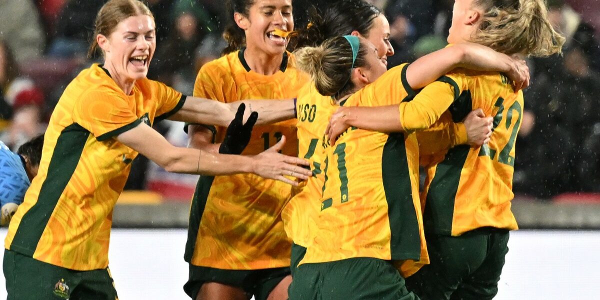 Australia's defender Charlotte Grant (R) is mobbed by teammates after scoring the team's second goal during the International football friendly match between England and Australia at the Gtech Community Stadium in Brentford, west London on April 11, 2023. (Photo by Glyn KIRK / AFP)