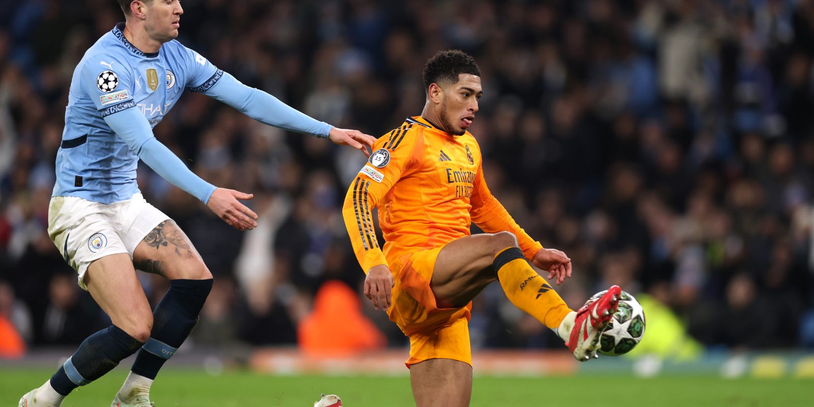 MANCHESTER, ENGLAND - FEBRUARY 11: Jude Bellingham of Real Madrid scores his team's third goal whilst under pressure from John Stones of Manchester City during the UEFA Champions League 2024/25 League Knockout Play-off first leg match between Manchester City and Real Madrid C.F. at Manchester City Stadium on February 11, 2025 in Manchester, England. (Photo by Julian Finney - UEFA/UEFA via Getty Images)